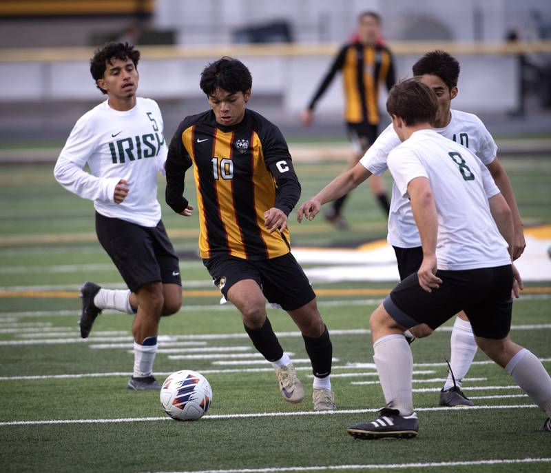 Herscher's Luis Parra, center, moves the ball past Bishop McNamara's Diego Perez, left, Jesus Arenas, background right, and Matthew Buzas, foreground right, in a regional match-up on Tuesday, October 21, 2025.