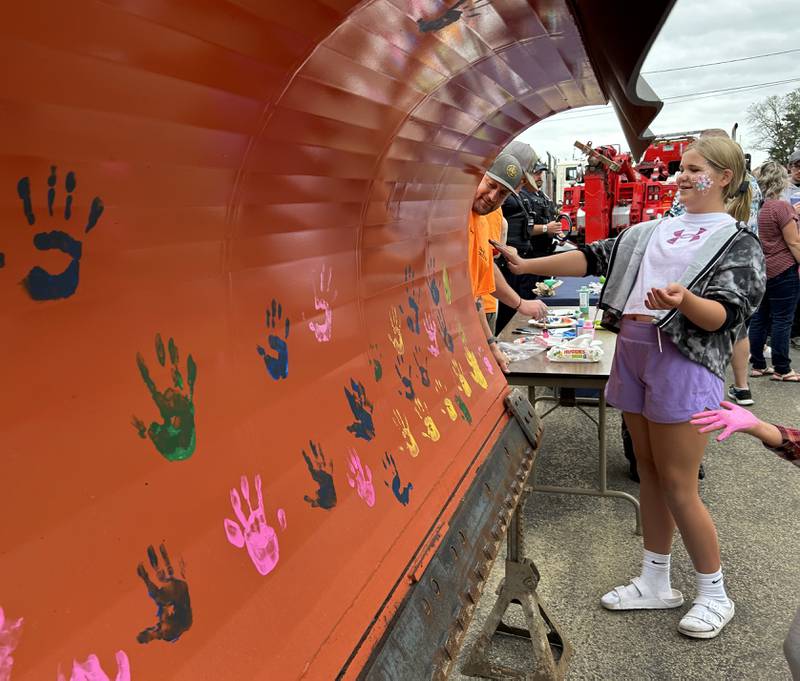 Taylor Stacy, 12, of Byron, decides where to make her hand print on the blade of an Oregon snow plow at the Oregon Police Department's National Night Out on Tuesday, Aug. 6, 2024. The event was co-sponsored by the Oregon Park District at River's Edge Experience.