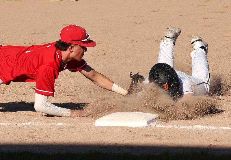 DeKalb's Matthew Clayton is out diving into third base as Naperville Central's Henry Paul dives to make the tag just in time during their game Tuesday, April 30, 2024, at DeKalb High School.