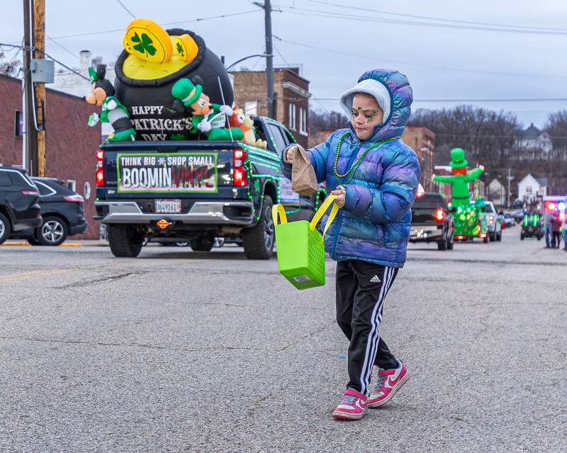 Harper Jordan puts bag thrown from parade into basket at the St. Patricks Day parade on Tuesday, March 14, 2026 on Main Street in Marseilles.