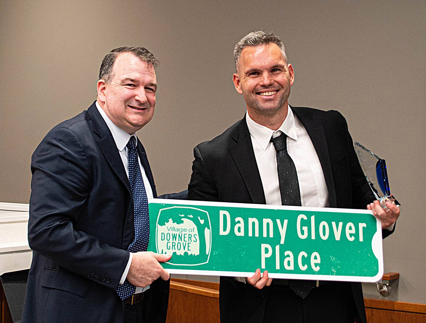 Downers Grove Commissioner Danny Glover (right) receives a commemorative street sign from Mayor Bob Barnett at Tuesday's village council meeting. Glover decided not seek reelection after serving one term on the council