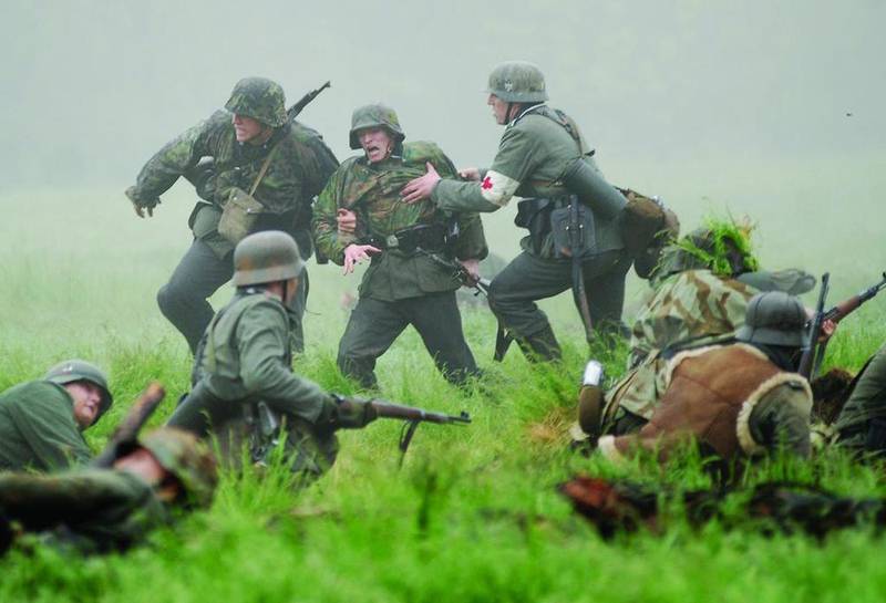 An "injured" solider is helped by his comrades during a World War II battle re-enactment at Stronghold Camp and Retreat Center near Oregon in 2017. The Midway Village in Rockford is hosting its annual World War II days Sept. 28-29.