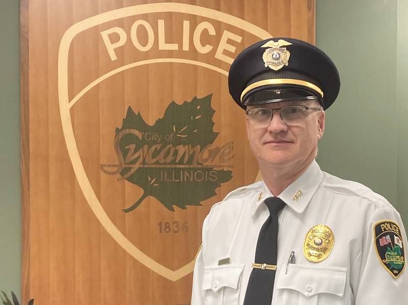 Retired Sycamore Police Deputy Chief Steve Cook poses next to the logo of the Sycamore Police Department. Cook was named the 2022 Friend of the Festival ahead of the Sycamore Pumpkin Festival. (Photo provided by Steve Cook).