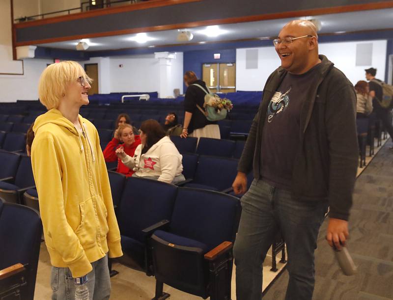 Woodstock High School senior Aaron Lush talks with graduate Alex Riak on Thursday, Dec. 7, 2023, during a rehearsal for the school's “Across the Universe” concert. Riak, who graduated in 2014 and now works as a professional composer in Los Angeles, created a piece titled “Unknown” for the concert.