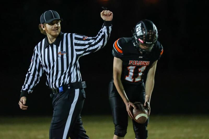 Connor Decker of Flanagan Cornell Woodland sets ball up for punt whilst referee holds up fist on Friday, October 25, 2024 at Flanagan High School in Flanagan.