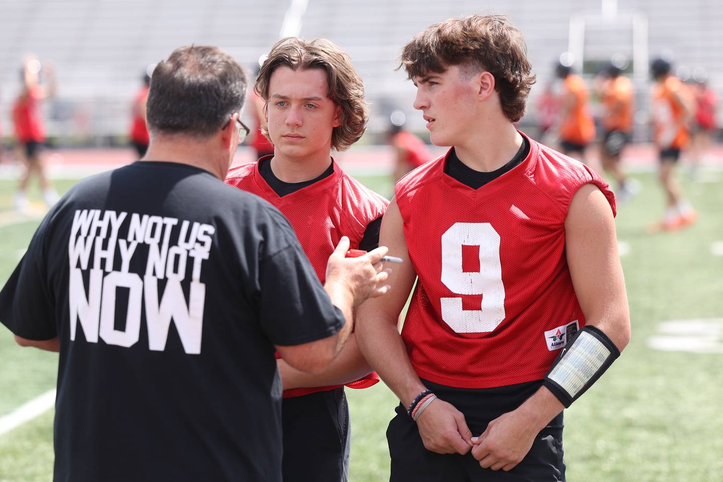 Lincoln-Way West quarterbacks Drew Litke, center, and Chase Hetfleisch listen to a coach during a 7-on-7 scrimmage at Lincoln-Way East on Tuesday, July 18th, 2023 in Frankfort.