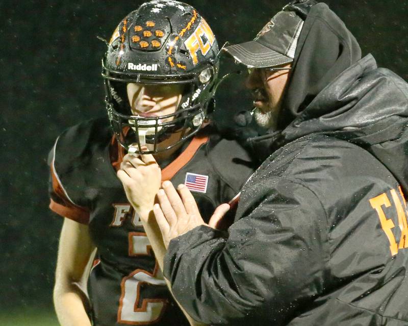 Flanagan-Cornell/Woodland quarterback Seth Jones talks with head coach Todd Reed before running a play during the first round of the 8-man football playoffs on Friday, Oct. 27, 2023 in Flanagan.
