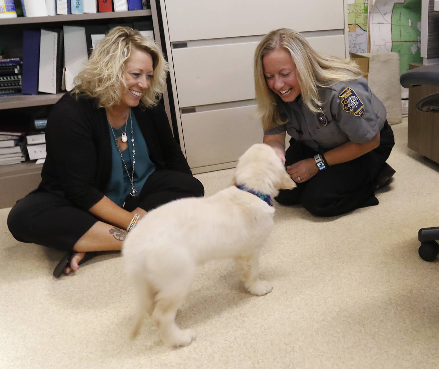 Les missionnaires Jenny Sink et Kelly Schmidt interagissent avec Oakley, le nouveau chien de thérapie du département de police de McHenry, le jeudi 4 août 2022, au département de police de McHenry.