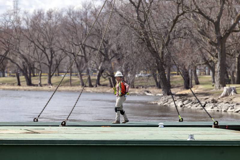 A temporary barge is laid across the Rock River Wednesday, March 26, 2025, as work on the pedestrian bridge continues.