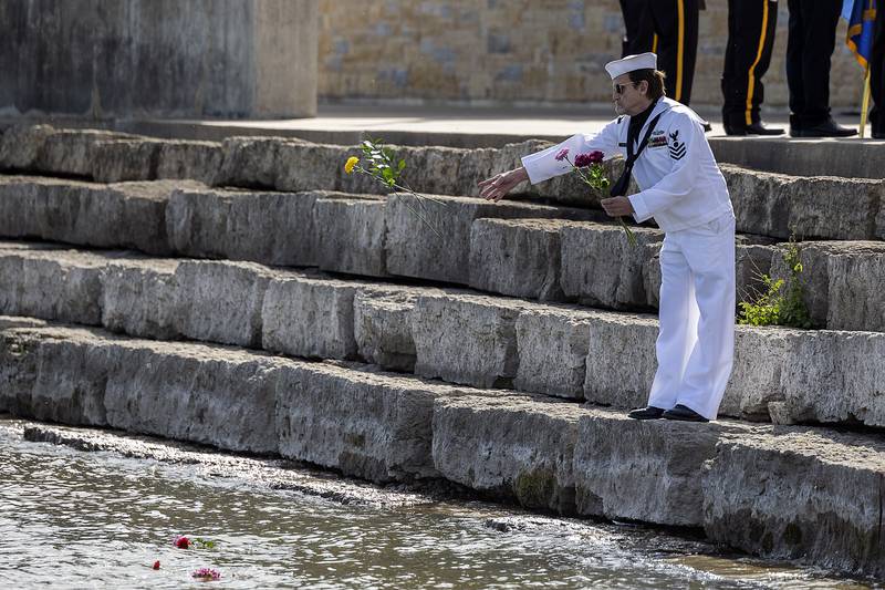 Dave Devine throws flowers into the Rock River in recognition of Memorial Day Monday, May 26, 2025, to honor those who died at sea.