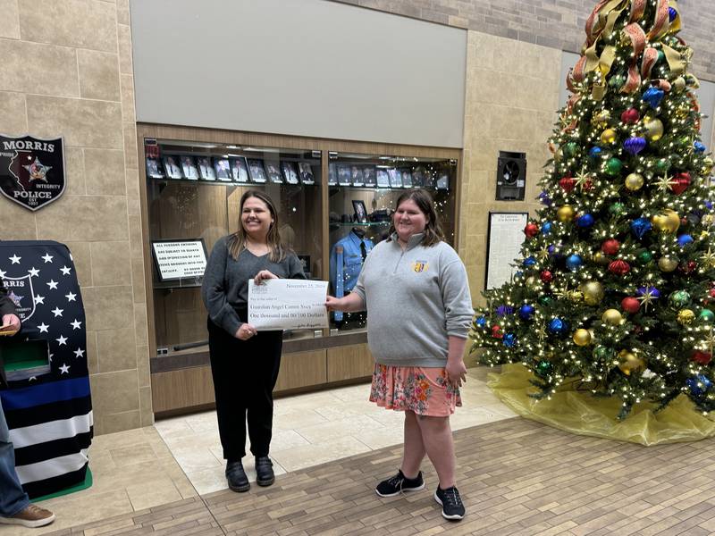Julia B., right, hands a $1,000 check to Allison Kukman from Guardian Angel Community Services.