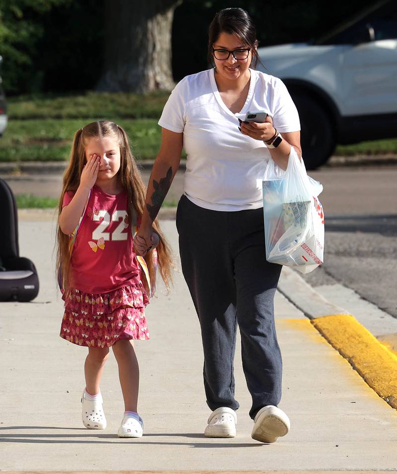 First grader Zaniyda Bourgoine looks a little tired as she arrives with her mom Jasmine Rodriguez Wednesday, Aug. 13, 2025, for the first day of school at Founders Elementary in DeKalb.