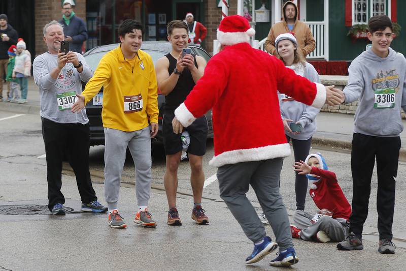 Jay McLean receives “high fives” as he runs to the finish line during the McHenry County Santa Run For Kids on Sunday morning, Dec. 3, 2023, in Downtown Crystal Lake. The annual event raises money for agencies in our county who work with children in need.