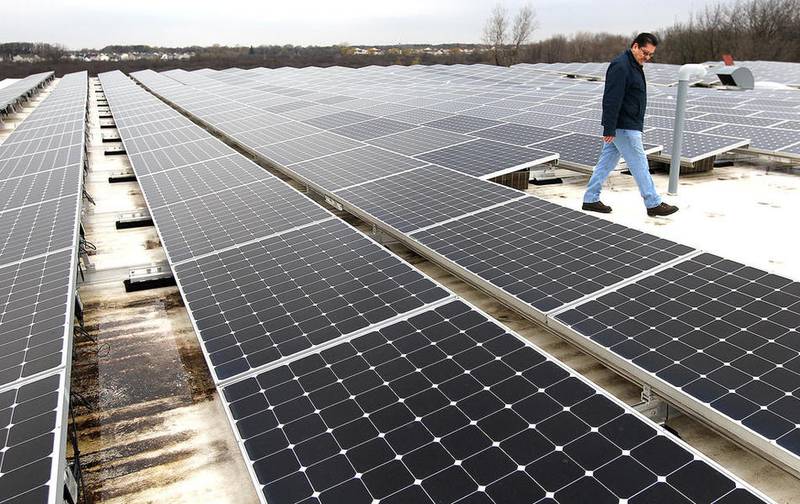 Northwest Herald file. Other World Computing facility maintenance technician Juan Valdez walks among a privately owned solar array on the roof of the Woodstock company.