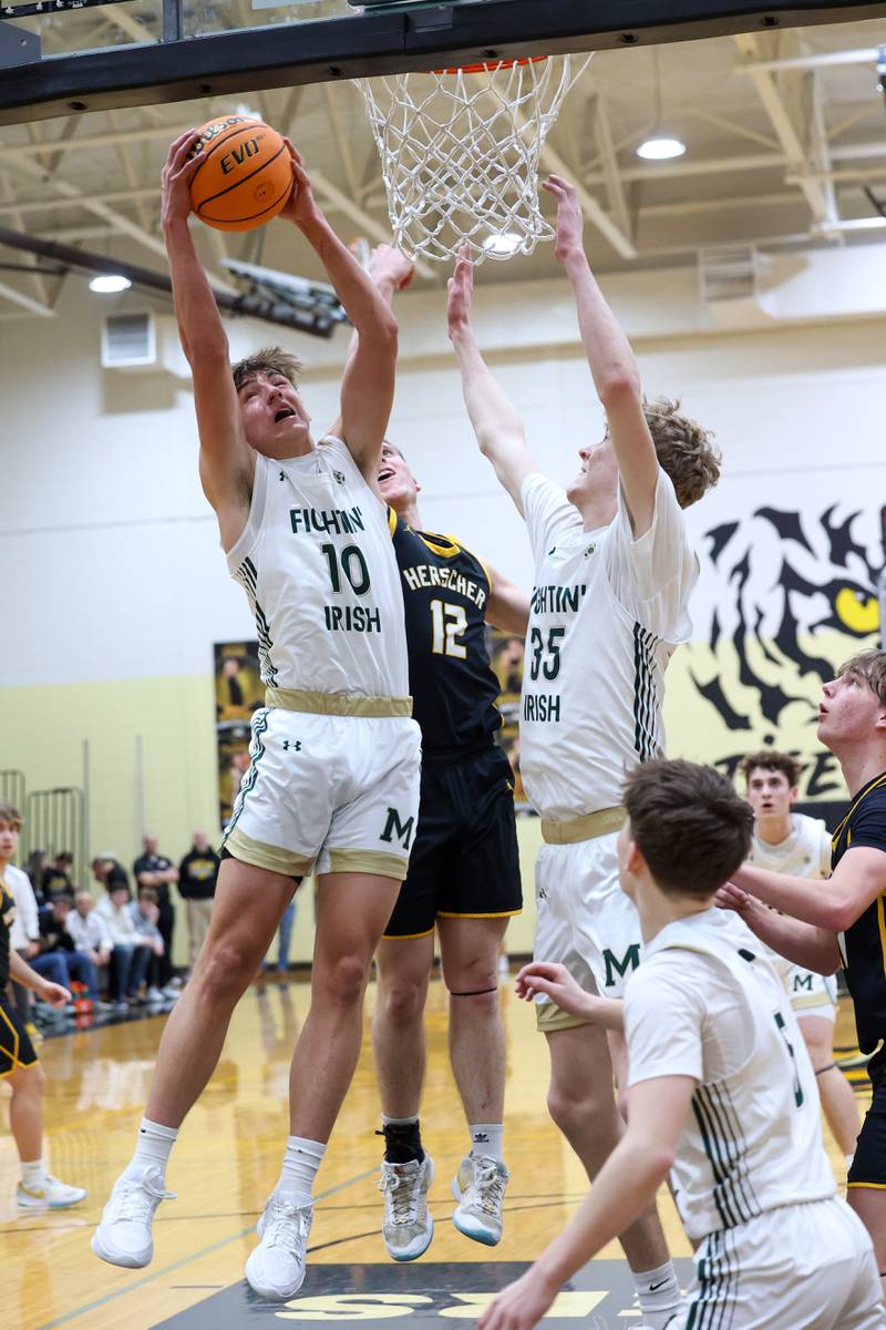 Bishop McNamara's Coen Demack grabs a rebound over Herscher's Gavin Hull during Bishop McNamara's 71-42 victory in the IHSA Class 2A Herscher Regional semifinal on Wednesday, Feb. 25, 2026.