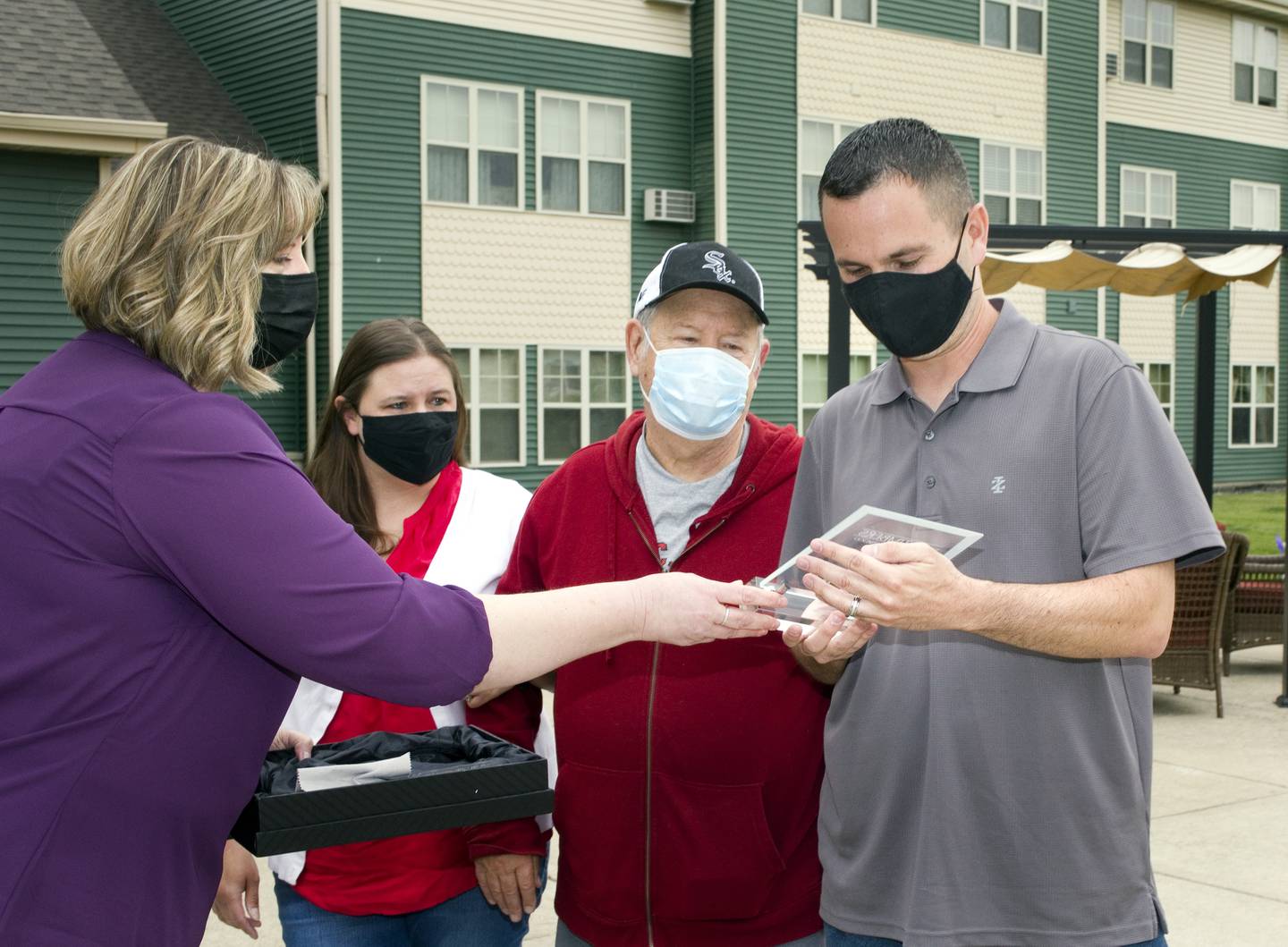 Amy Odell (left) director of activities of the Timbers of Shorewood, hands a recognition plaque to Joni Hilger’s son, Steve Hilger, as Joni’s daughter, Trisha Comiskey (not pictured), and husband, Tom Hilger, look on. Joni Hilger who was hit by a car and died instantly on June 4, 2020, was named Volunteer of the Year at Timbers of Shorewood. Because of COVID-19 restrictions, the Timbers was unable to honor her last June. The event was held outdoors with family members and staff on Saturday, May 8, 2021.