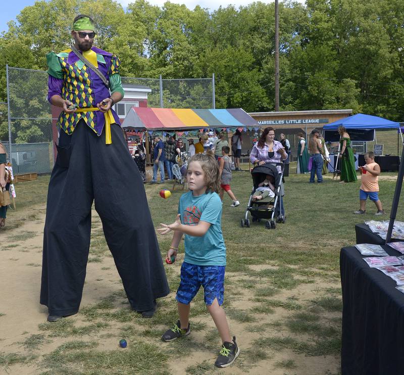 Ethan Metcalfe learns Hacky Sack from the Stilt Walker Saturday during the annual Marseilles Renaissance Faire.