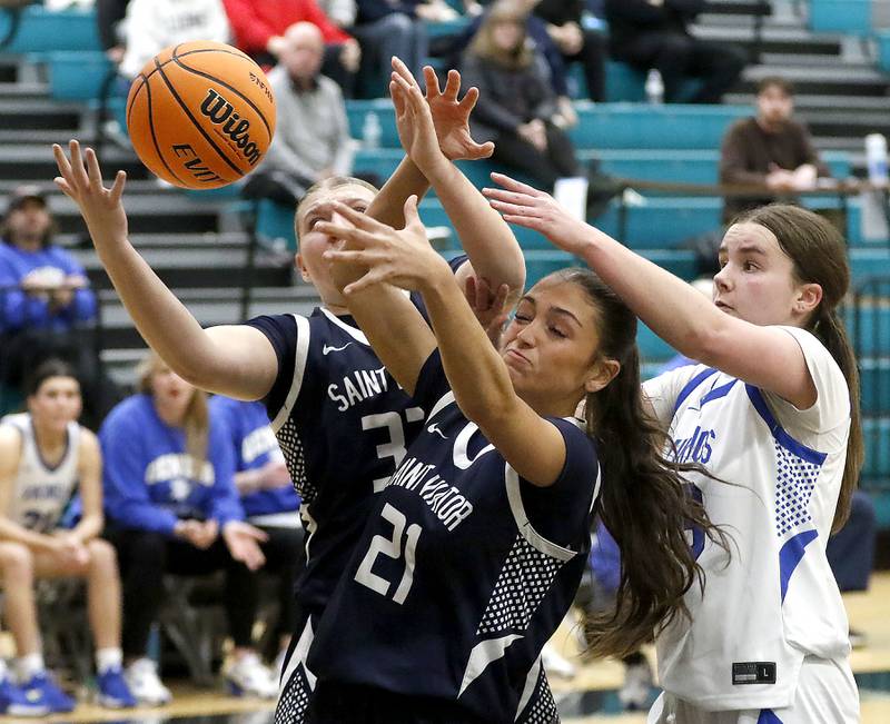 St. Viator's Ava Garcia, and Gabriella Scaravalle battle Geneva's Nora Hatton for q rebound during the IHSA Class 3A Woodstock North Supersectional girls basketball game on Monday, March 2, 2026, at Woodstock North High School.