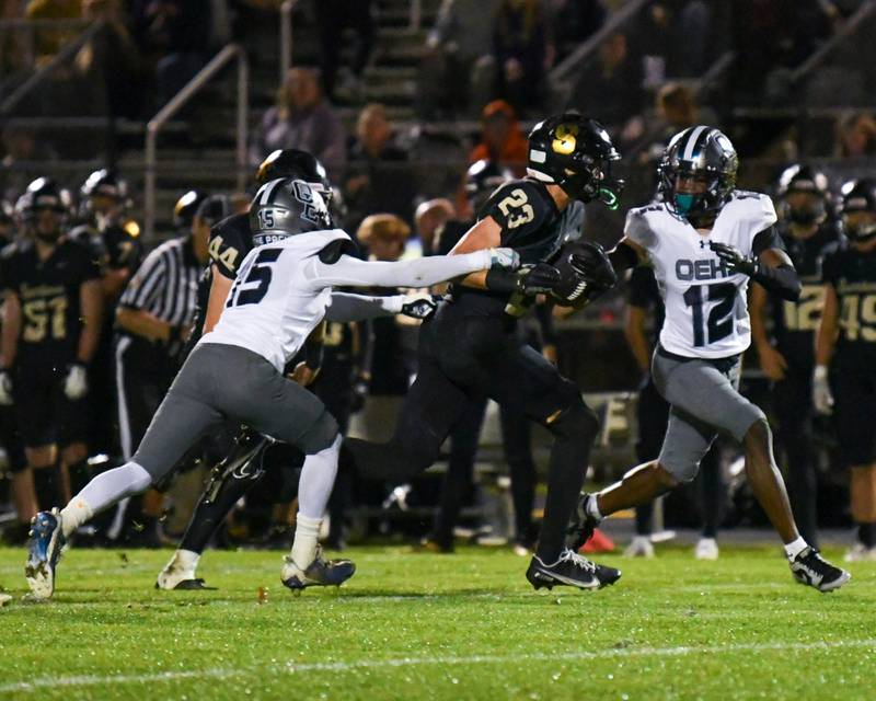 Sycamore's Dylan Hodges, center, slips through the fingers of Oswego East's Jamari Mckay, left, before being tackled by Oswego East's Nigel Grisby (12) a few yards later during the game on Friday Sept. 2024, held at Sycamore High School.