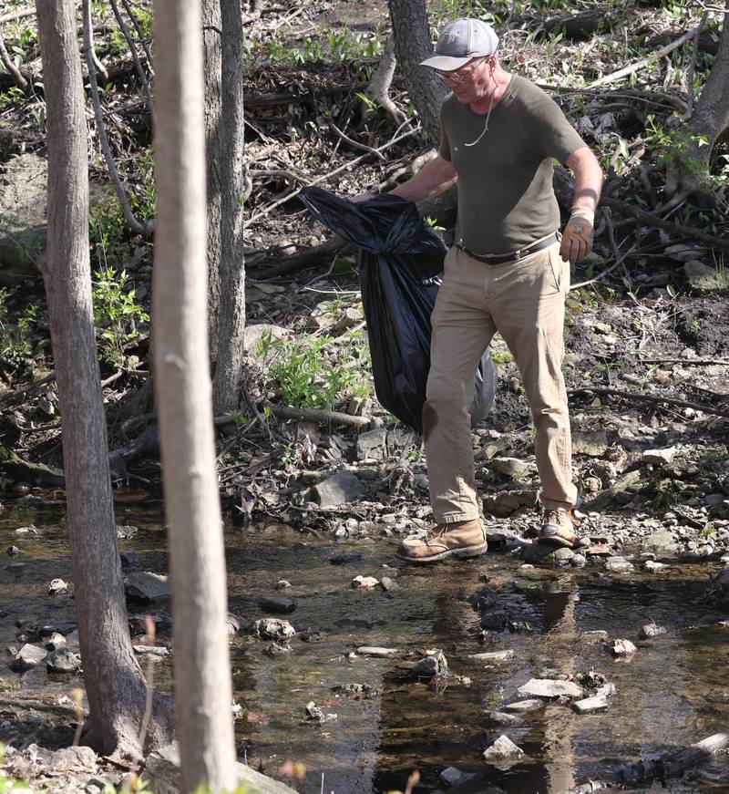 DeKalb Park District Board Vice President Dag Grada looks for trash to pick up Monday, April 22, 2024, during an Earth Day Clean Up event at Hopkins Park in DeKalb.