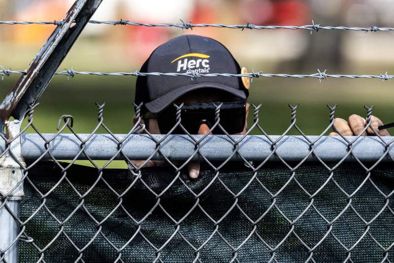 A contractor places black fabric along the fencing around the perimeter of the grounds of the Joliet Local Training Area site for the Illinois National Guard at 20612 Arsenal Road in Elwood on Wednesday, October. 8, 2025.