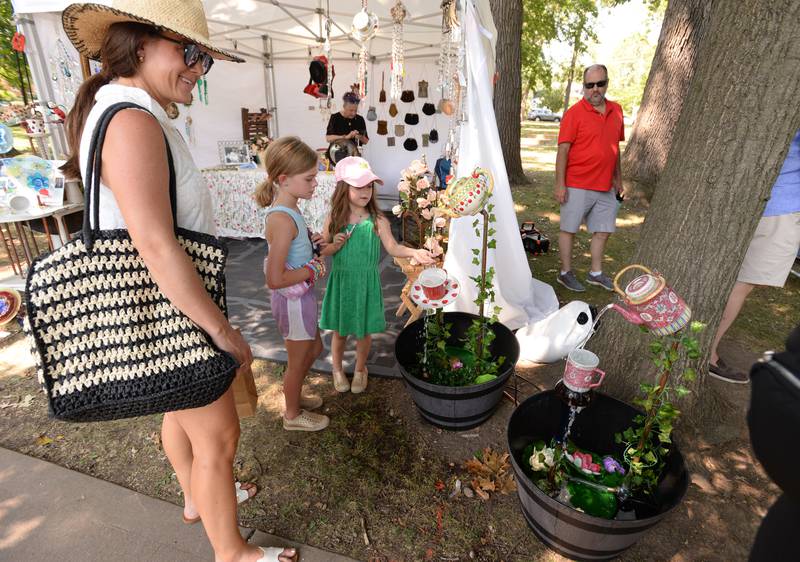 Maureen Jasculca and her children Cecelia and Evie admire one of the water fountain pieces of ceramic art work during the Glen Ellyn Art Festival on Sunday, Aug 24, 2024 at Lake Ellyn.