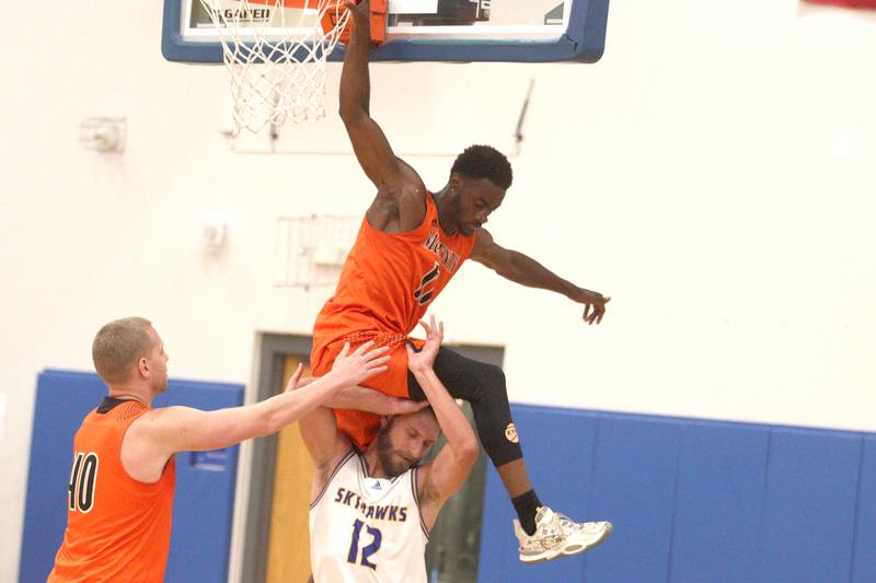 McHenry’s Maki Mohr lands on Johnsburg’s Tanner Kreassig after attempting a dunk during an alumni basketball game at Johnsburg High School Saturday evening. McHenry’s Brian Madson, left, helps the players get untangled.