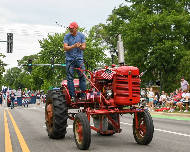Will Kupish of Downers Grove tries to pump up the community members during the Independence Day parade on Friday July 4, 2025, in downtown Downers Grove as he drives his 1954 Super A Farmall tractor.