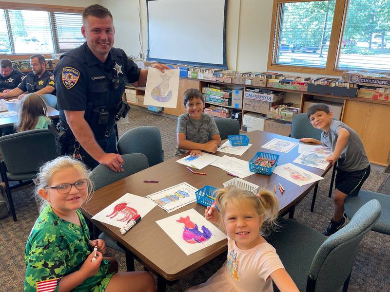 Yorkville Police Department Officer Kyle Borowski and children showcase their art at last year's 'Color with Cops' at the Yorkville Public Library.