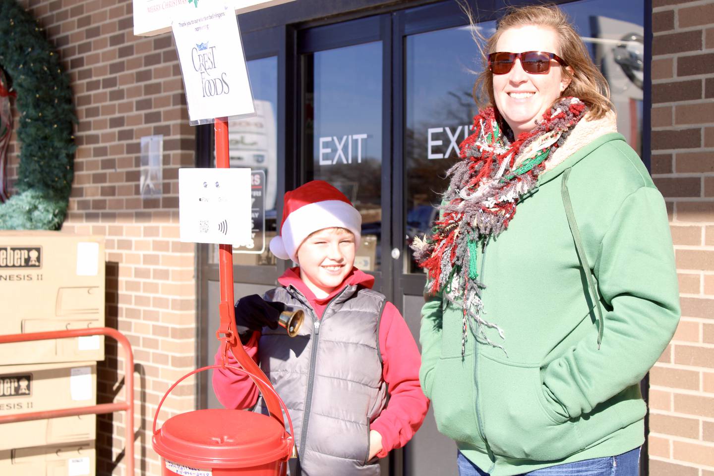 Henry Fransen, age 8, and Jackie Fransen serve as bell ringers representing Crest Foods at The Salvation Army kettle outside Ace Hardware in Dixon on Saturday.