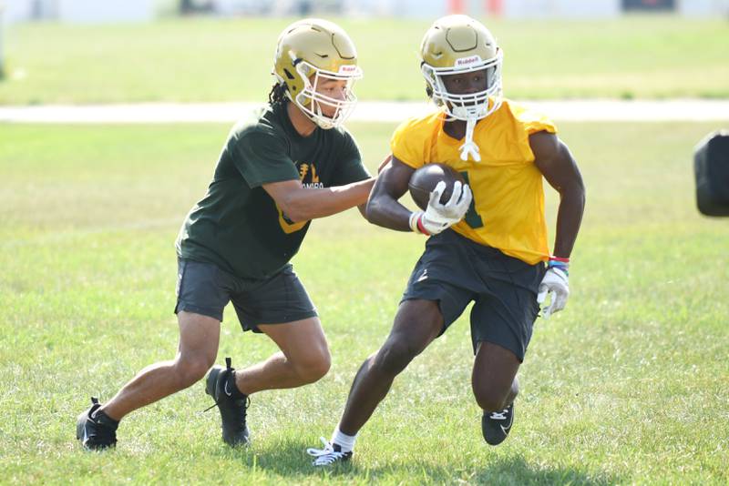 Bishop McNamara's Micah Lee, left, hands the ball to Malachi Lee during practice Monday, Aug. 11, 2025.