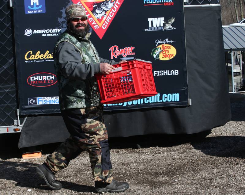 Tim Schwingle carries his basket of fish across the stage during the National Walleye Tour Masters Walleye Circuit on Saturday, March 23, 2024 in Spring Valley.