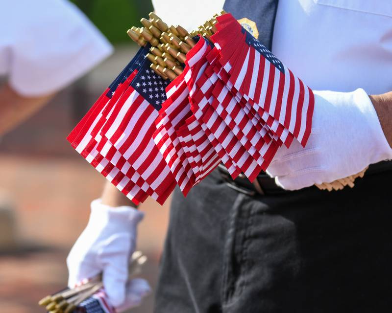 An American Legion Post No. 66 member holds flags to hand out during the Memorial Day parade route in downtown DeKalb held on Monday, May 30, 2022.