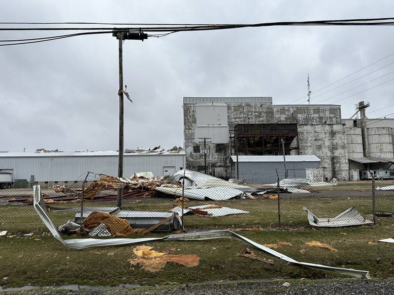 A roof is partially ripped off of a warehouse from the severe weather just south of Mendota on Saturday, April 1, 2023. Sheet metal and other materials cover the ground outside of the warehouse.