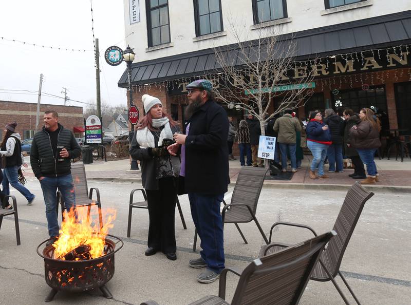 Wine enthusiasts warm up to a fire during the Winter Wine Walk on Saturday, Feb. 8, 2025 in Utica.