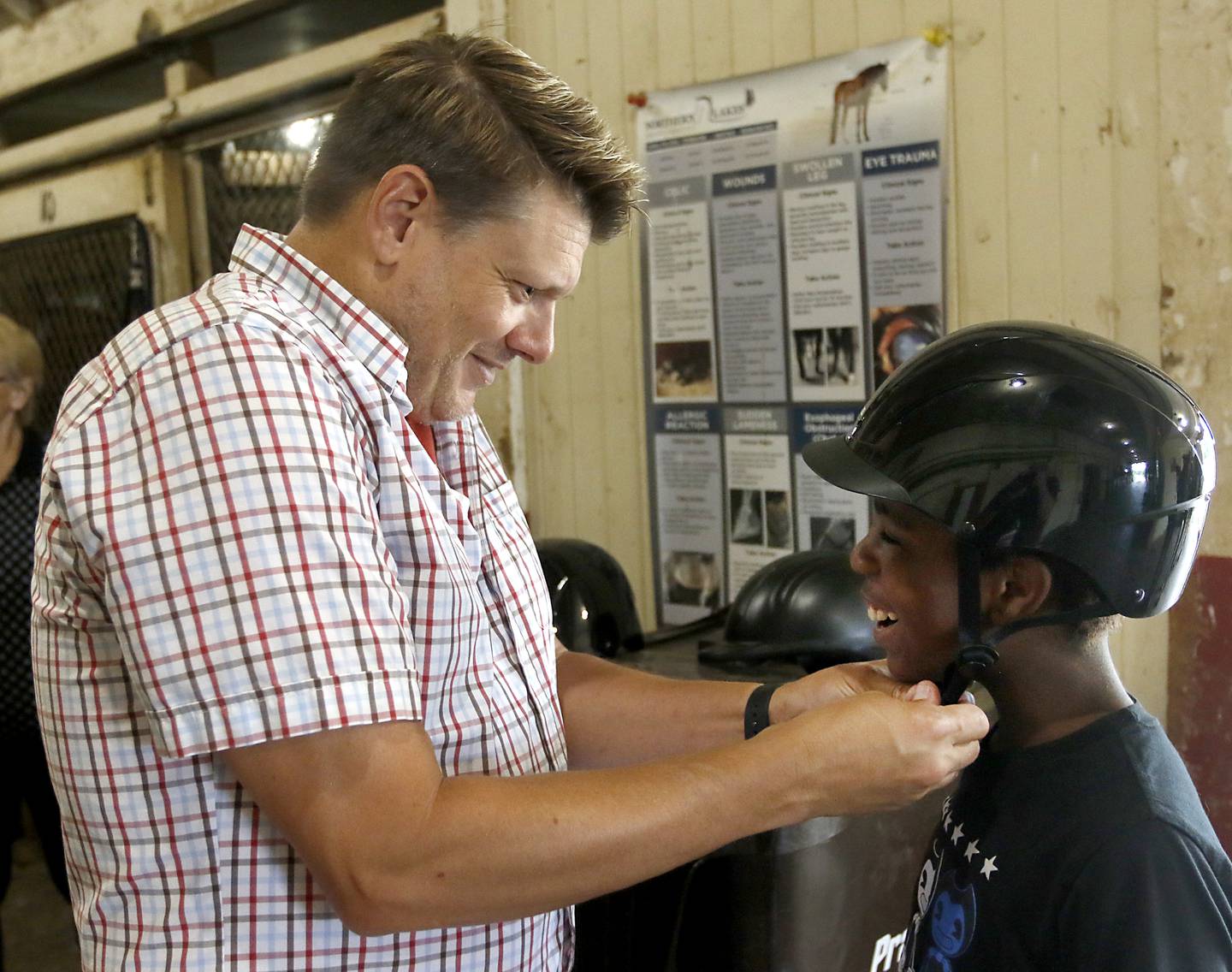 Dan Taylor puts a helmet on his son, Richard Taylor-Terry, 11, before his riding lesson Friday July, 8, 2022, at the R Double J Ranch, 2800 Derby Lane, in McHenry. The R Double J Ranch recently got the contract to operate this equine facility from McHenry with the goal of making it more of a community-centric center and make learning about horses and riding open to all.