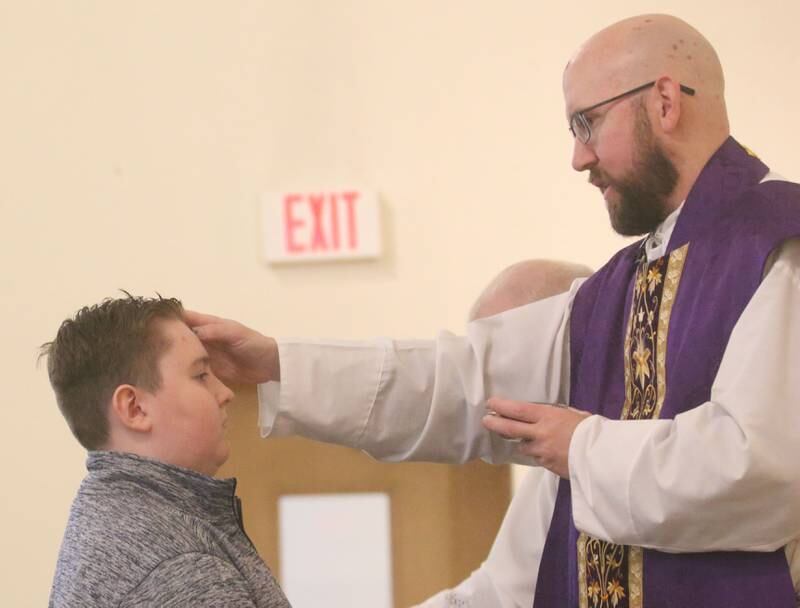 The Very Rev. Father Tom Otto places ashes on the forehead of Jackson Layhew, a student at Trinity Catholic Academy during Ash Wednesday Mass on Wednesday, March 5, 2025 at the Queen of the Holy Rosary Church in La Salle.