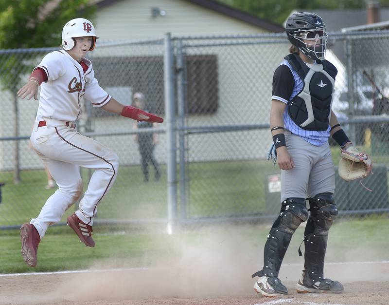 La Salle-Peru’s Mason Lynch looks to first base to see if a runner is safe and making his slide into home on Monday, May 22, 2023 in Oglesby.