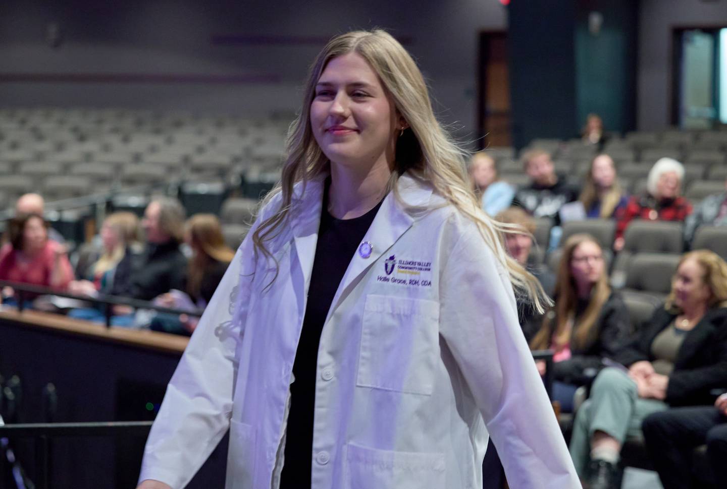 The first class of eight dental hygiene students to graduate from Illinois Valley Community College accepted white lab coats and lapel pins to signify their entry into the field during a ceremony on December 12, 2025.
