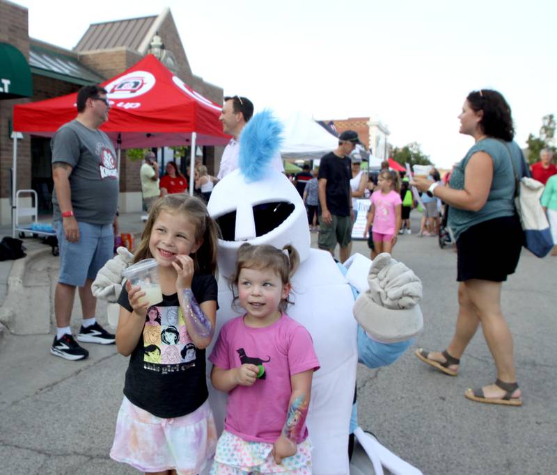 Adeline Walker, 2, right, and her sister Evelyn, 5, of Crystal Lake pose with the Canterbury Elementary School Knight mascot during National Night Out in downtown Crystal Lake on Thursday, Aug. 7, 2025.