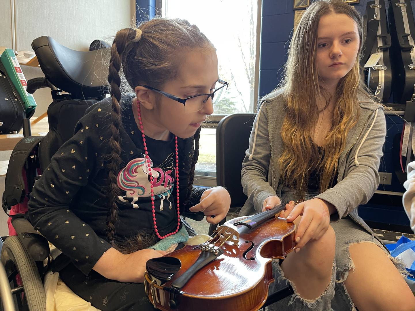 Karissa Ulsaver (right) guides Liezl Eternick (left) in playing the violin on Friday, Jan. 13, 2023, at Creekside Middle School, as part of the United Sound program. United Sound is geared toward removing social barriers through music. At Creekside, it provides students in special education the opportunity to learn how to play while receiving social interaction.
