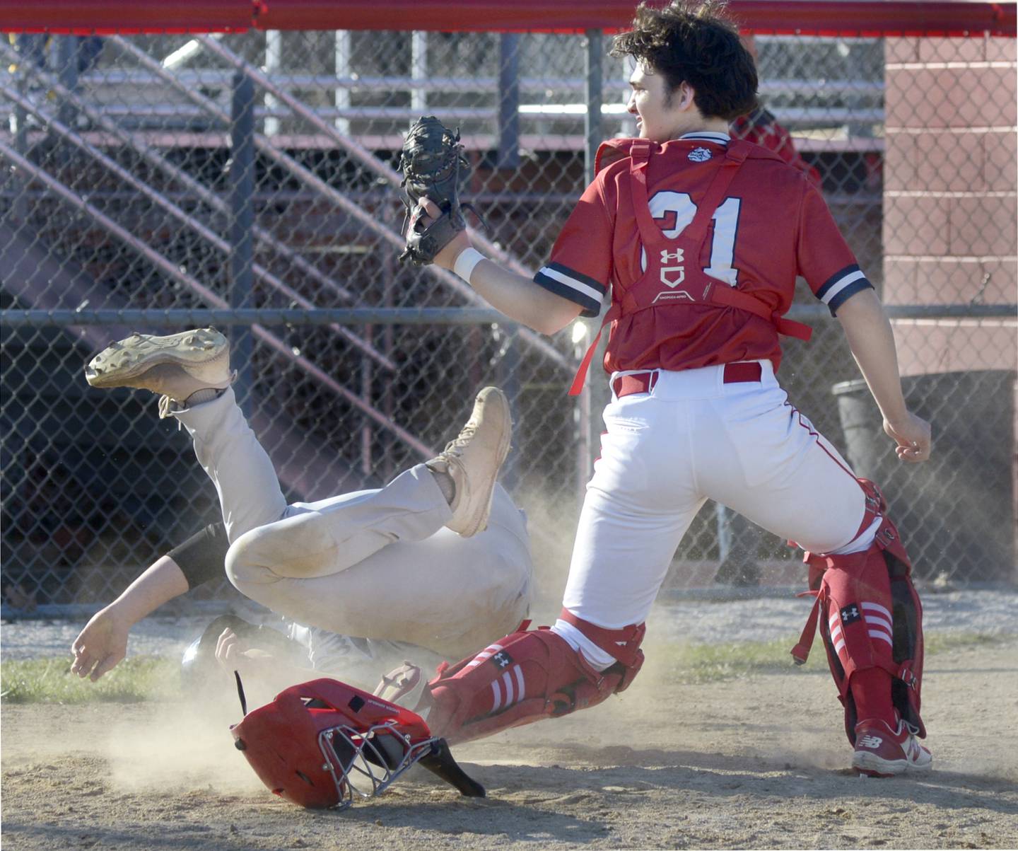 As Plainfield’s Evan Carey goes tumbling at the plate, Streator catcher Jarred Clark looks to the umpire for out call in the 3rd inning Tuesday at Streator.