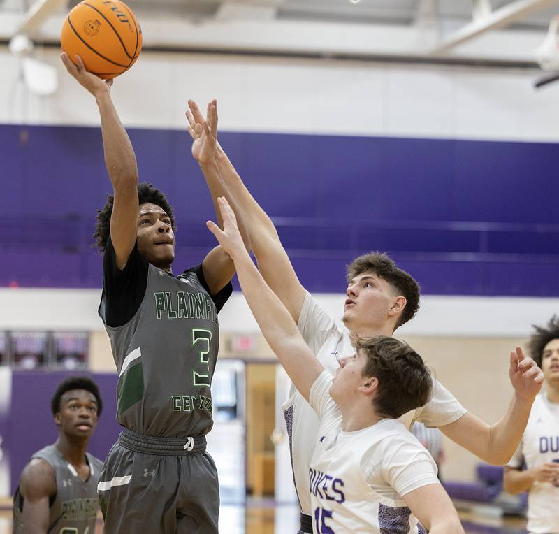 Plainfield Central’s Zion Finch puts up a shot against Dixon’s Jackson Koehler and Jimi Gosinski Friday, Jan. 3, 2025, at Dixon High School.