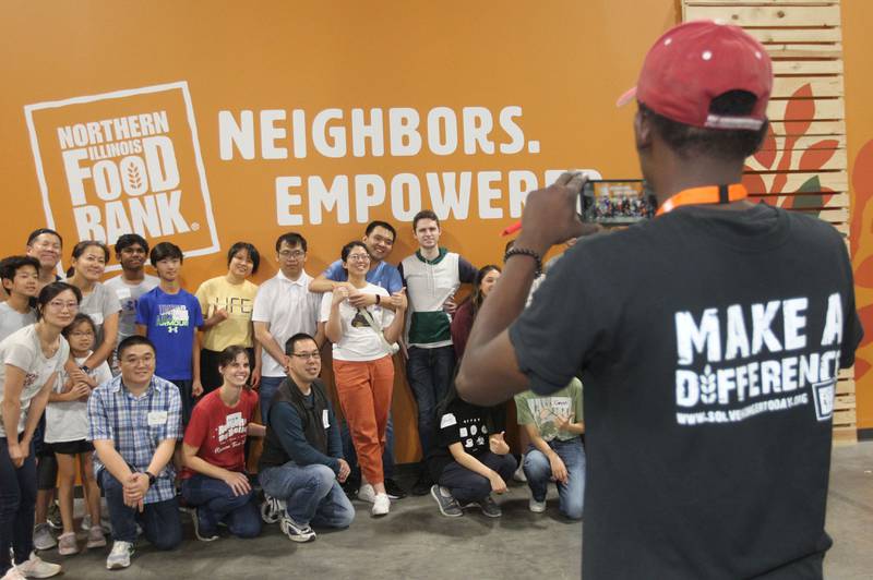 Derrick McCoy, of Waukegan, warehouse operations, takes a photo of a team of volunteers who finished their shift sorting and labeling large cans of vegetables at the Northern Illinois Food Bank on August 19th in Lake Forest. The North Suburban Center recently celebrated it’s one-year anniversary at this location.  
Photo by Candace H. Johnson for Shaw Local News Network