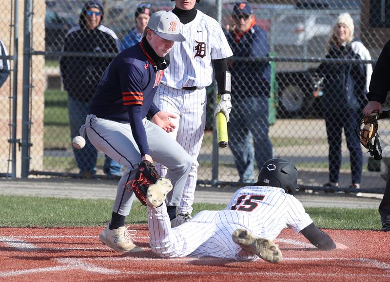 DeKalb's Paul Kakoliris scores on a wild pitch as Naperville North's Max Steele can’t handle the throw Tuesday, April 15, 2025, during their game at DeKalb High School.