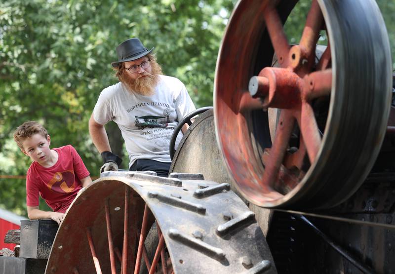 Rhys Baker, (right) from Sun Prairie, Wis., and Lucas Malsch, 9, from Burlington, Wis., run an 18 horsepower Advance Rumely engine to power the sawmill Thursday, Aug. 7, 2025, at the 68th annual Sycamore Steam Show and Threshing Bee at Taylor Marshall Farm on Lukens Road in Sycamore.