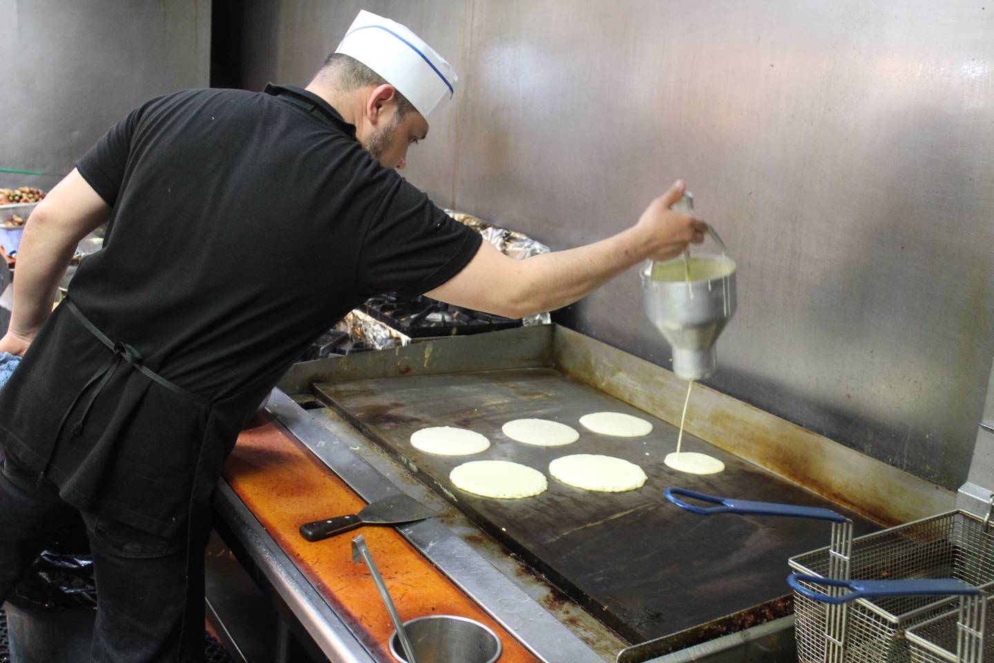 An Around the Clock cook starts a batch of pancakes on May 15, 2025.