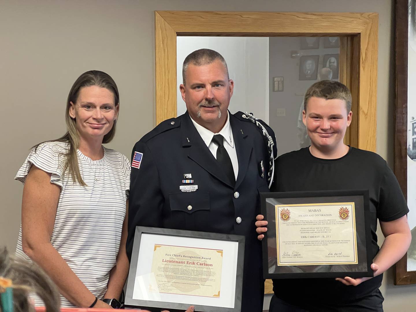 Sycamore firefighter, Lieutenant Erik Carlson, stands with his wife, Sarah Carlson, and his son, John Carlson, after being given two awards on Sept. 2, 2025, during a Sycamore City Council meeting.