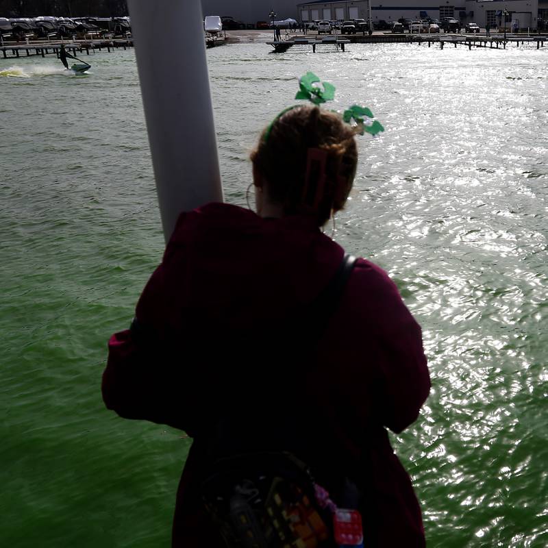 A girl watches as a jet skier, dressed as a leprechaun, stirs dye into the Fox River as the river is dyed green during the ShamROCKS the Fox Festival in McHenry on Saturday, March 16, 2024.