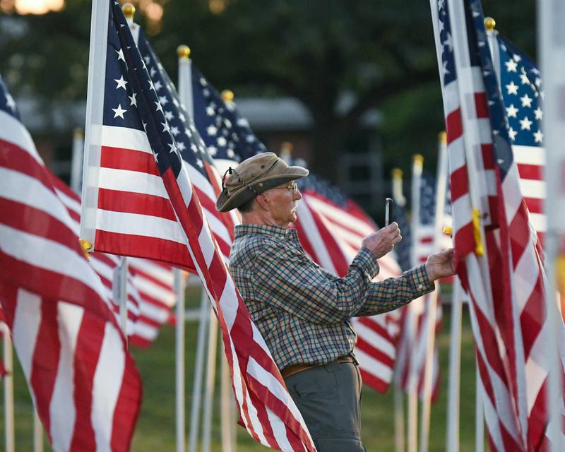 Cliff Cassidy of Naperville takes a photo of his dad’s dog tag on Sunday Sep. 3, 2023, during the opening ceremonies of Field of Honor at Denning Park in La Grange where 500 American flags that are on display to honor veterans, active military, first responders as well as frontline workers.